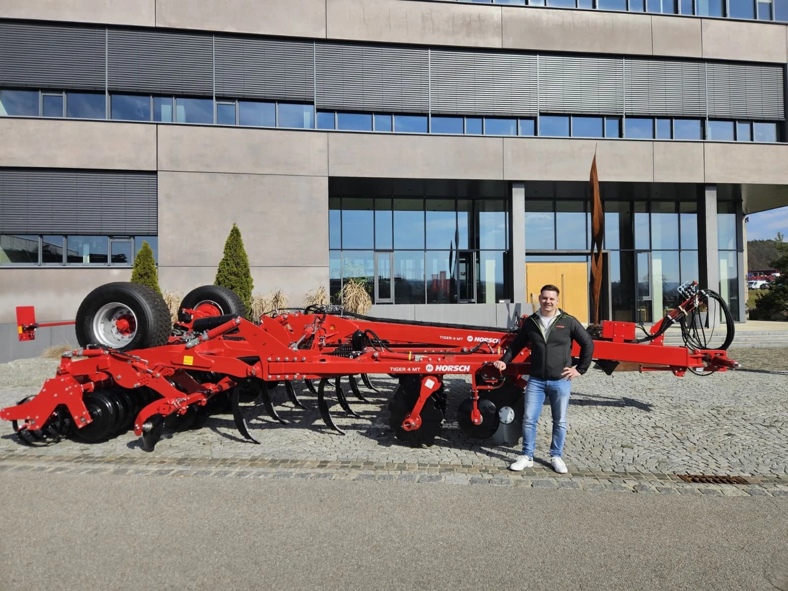 Verkäufer Alexander Wind von Landtechnik Schuster bei der HORSCH Schulung im März, im Hintergrund ein HORSCH Tiger.